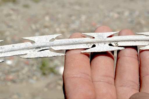 A piece of the barbed wire making Morocco - Ceuta (EU external land border). In the small Moroccan border town of Belyounech, fragments of the land border are scattered on the beach making it impossible to walk or swim barefooted. © Saâdia Dinia 2017.