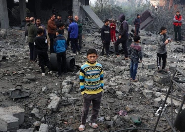 Palestinian child standing on the backdrop of destroyed buldings from Israeli attacks