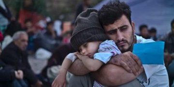 Syrian refugee holding his son