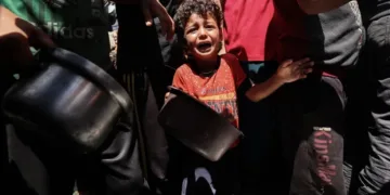 A child cries as Palestinians gather to receive a meal at a food distribution point in the Nuseirat camp for refugees in the central Gaza Strip on May 24 [Eyad Baba/AFP]