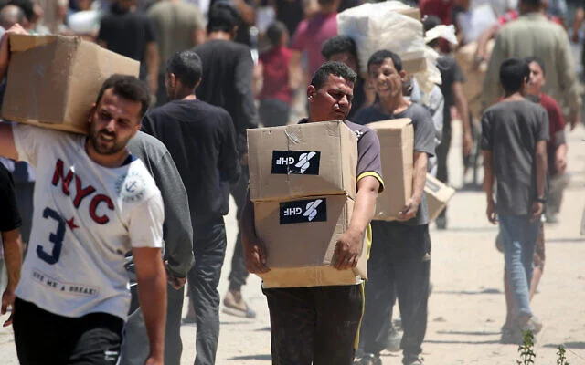People carry boxes of relief supplies distributed by the US- and Israel-backed Gaza Humanitarian Foundation at an aid distribution center in the central Gaza Strip on May 29, 2025. (Eyad BABA / AFP)