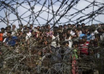 Rohingya refugees gather behind a barbed-wire fence in the “no-man’s land” border zone between Myanmar and Bangladesh, April 25, 2018. © 2018 Ye Aung Thu/AFP/Getty Images