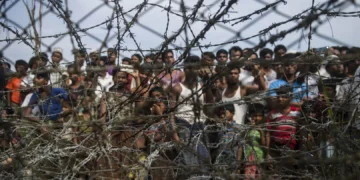 Rohingya refugees gather behind a barbed-wire fence in the “no-man’s land” border zone between Myanmar and Bangladesh, April 25, 2018. © 2018 Ye Aung Thu/AFP/Getty Images