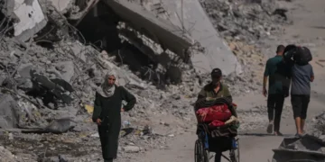 Palestinians walk through the destruction caused by the Israeli air and ground offensive in the Shati camp, in Gaza City, on Friday, October 24, 2025 [Abdel Kareem Hana/AP]