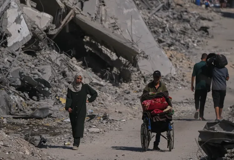 Palestinians walk through the destruction caused by the Israeli air and ground offensive in the Shati camp, in Gaza City, on Friday, October 24, 2025 [Abdel Kareem Hana/AP]