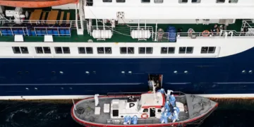 Passengers watching as health personnel assist patients onto a boat from the cruise ship MV Hondius, while stationary off the port of Praia, Cape Verde, on Wednesday Photograph: AFP/Getty Images