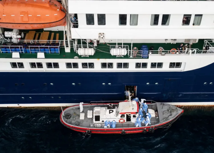 Passengers watching as health personnel assist patients onto a boat from the cruise ship MV Hondius, while stationary off the port of Praia, Cape Verde, on Wednesday Photograph: AFP/Getty Images