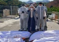 A man, accompanied by funeral workers, prays over the bodies of migrants who died while trying to cross from Morocco to Ceuta, on 21 August 2026. AP/Antonio Sempere