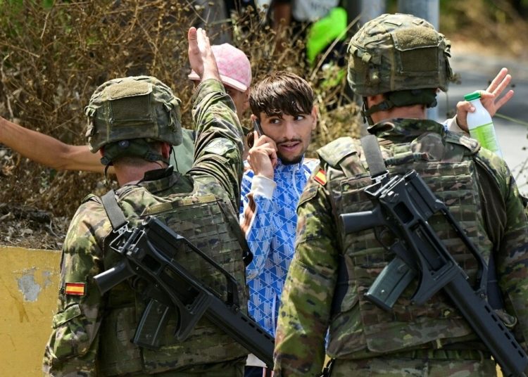 Spanish soldiers with migrants in Ceuta. [File: Fabian Bimmer/Reuters]