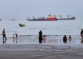 People spend time at a beach as commercial vessels are anchored in the Strait of Hormuz off Bandar Abbas, Iran, Wednesday, Aug. 5, 2026. (Amirhosein Khorgooi/ISNA via AP)