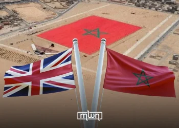 Moroccan and British flags pictured against an aerial backdrop of Western Sahara featuring a giant Moroccan flag. (Designed by MWN team)