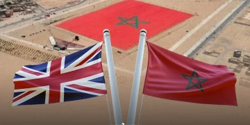 Moroccan and British flags pictured against an aerial backdrop of Western Sahara featuring a giant Moroccan flag. (Designed by MWN team)