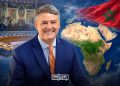 Hervé Verhoosel pictured against a backdrop featuring the UN Security Council chamber, a map of Africa and the Middle East, and the Moroccan flag. (Designed by MWN team)