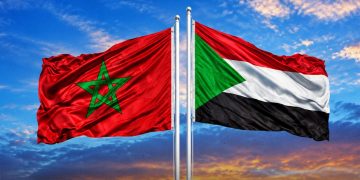 A graphic showing the Moroccan and Sudanese flags flying side by side against a dramatic sky, by MWN Design Team.