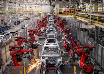 Industrial robots assemble vehicle bodies on an automated production line, highlighting the advanced manufacturing technology driving the automotive industry.