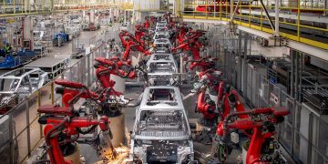 Industrial robots assemble vehicle bodies on an automated production line, highlighting the advanced manufacturing technology driving the automotive industry.