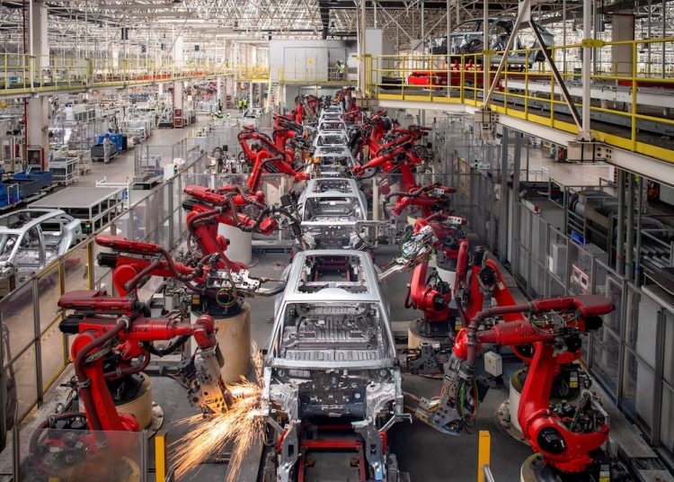 Industrial robots assemble vehicle bodies on an automated production line, highlighting the advanced manufacturing technology driving the automotive industry.