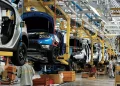 Workers assemble vehicles along an automotive production line at a manufacturing plant.