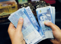 A person counts stacks of Moroccan 200-dirham banknotes.