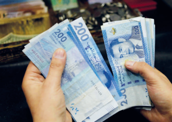 A person counts stacks of Moroccan 200-dirham banknotes.