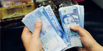 A person counts stacks of Moroccan 200-dirham banknotes.