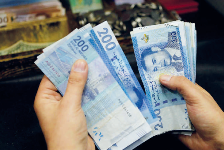 A person counts stacks of Moroccan 200-dirham banknotes.