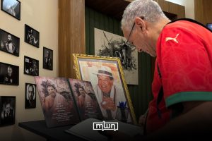 A visitor signs a condolence book beside portraits of Mohamed Slitine during the memorial tribute in Marrakech.