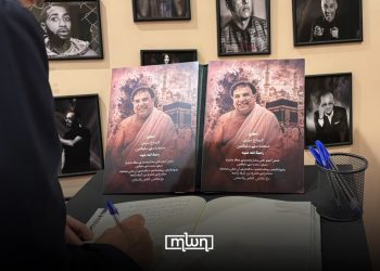 A visitor signs a condolence book beside portraits of Mohamed Slitine during the memorial tribute in Marrakech.