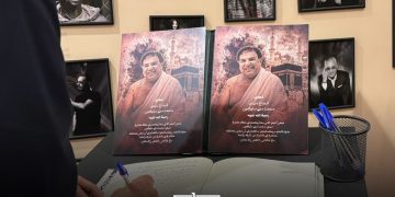 A visitor signs a condolence book beside portraits of Mohamed Slitine during the memorial tribute in Marrakech.
