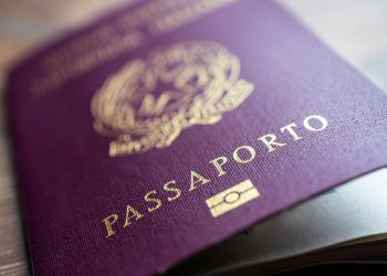 A close-up of an Italian passport, featuring its burgundy cover, gold national emblem, and the word “Passaporto.”