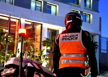 A Moroccan police officer stands beside a police motorcycle during an evening security operation.