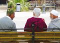 Three elderly men sit together on a public bench in Morocco.