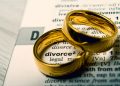 Two gold wedding rings rest on a dictionary page displaying the word “divorce,” symbolizing the end of a marriage.