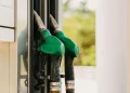 Two green fuel pump nozzles at a gas station, illustrating gasoline and diesel distribution.