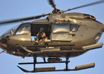 An armed member of Morocco’s Royal Gendarmerie sits at the open doorway of a Eurocopter EC145 helicopter in flight.